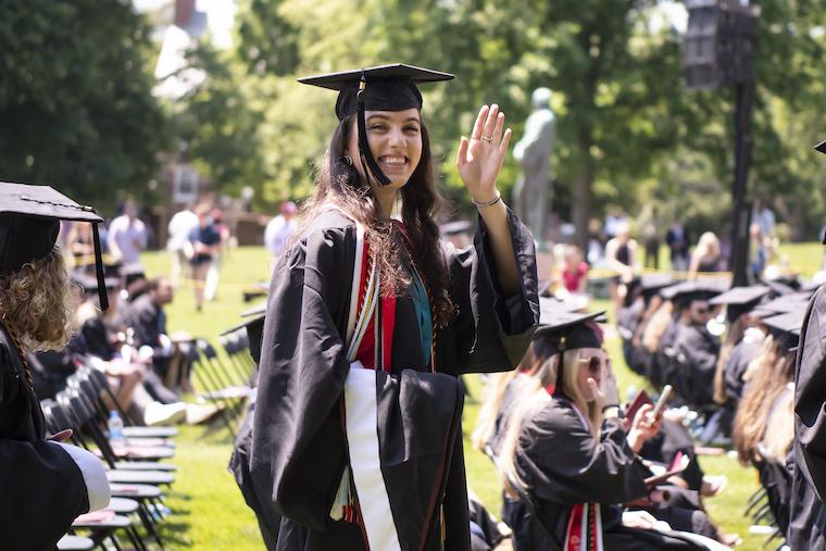 a graduate waves at the camera